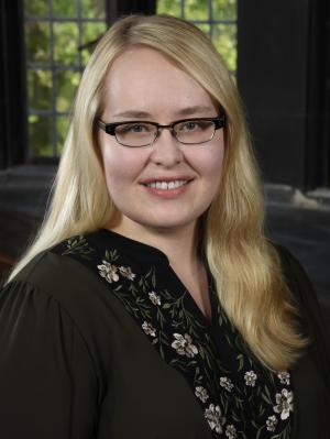 woman with long hair in a black shirt in front of a window