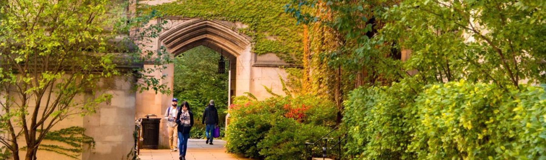 Students walking under arch and garden